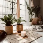 A white room with multiple layers of green plants and a boho rug in the middle with a candle on top.