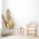 decorative chair, table, and plant alongside a white wall.